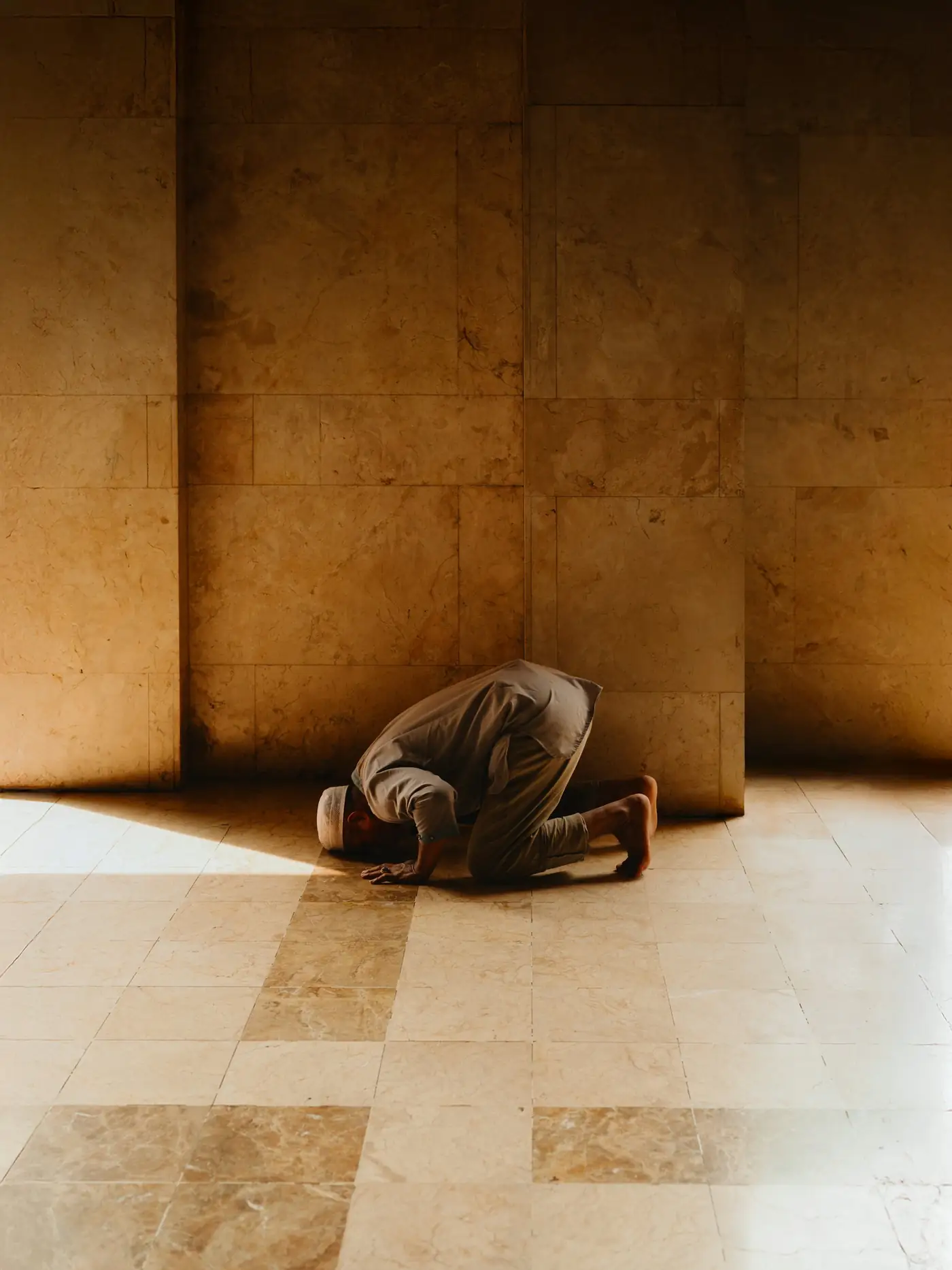 A man in prayer inside a sunlit mosque