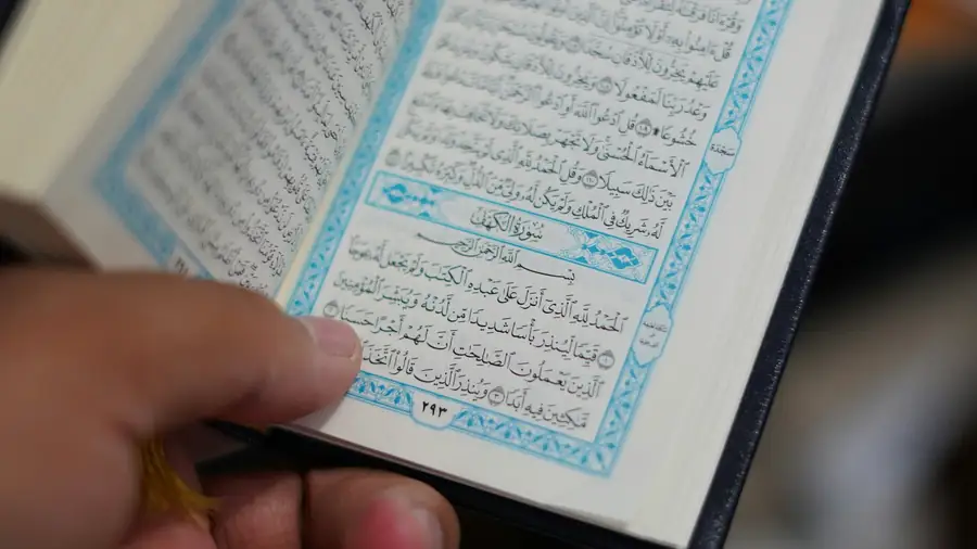 A hand holding an open Quran